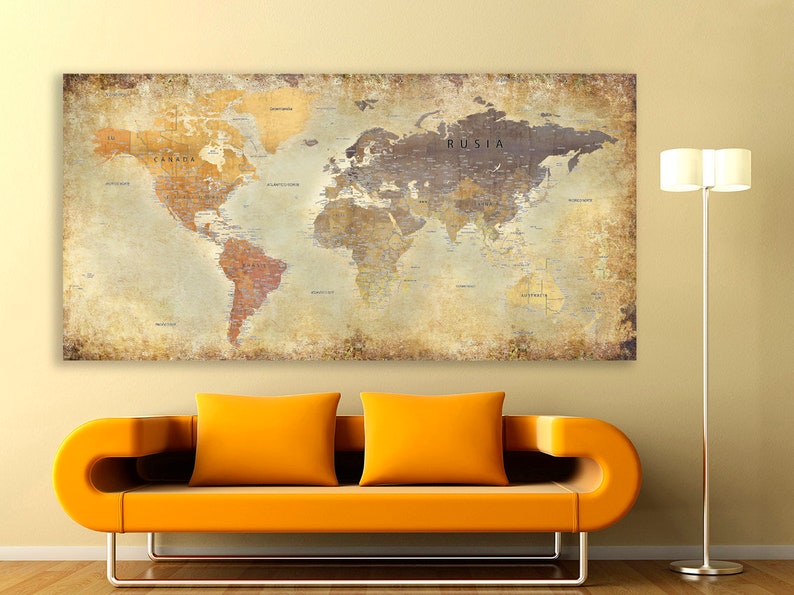 May include: A vintage-style world map print with a distressed, aged look. The map is printed on a canvas and features a light brown background with a dark brown outline of the continents. The map includes the names of countries and major cities. The map is hanging on a wall above a yellow couch.