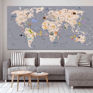May include: A large world map canvas print with a grey background. The map shows continents in beige, with animal illustrations and country names. The print is displayed above a grey sofa with two wooden side tables.