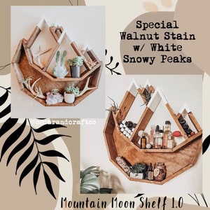 May include: A wooden mountain-shaped shelf with a walnut stain and white snowy peaks. The shelf is filled with small plants, crystals, and decorative items. The text on the image reads "Special Walnut Stain w/ White Snowy Peaks" and "Mountain Moon Shelf 1.0".