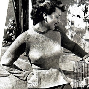 May include: A black and white photo of a woman wearing a knitted sweater. The sweater is a light gray color and has a ribbed texture. The woman is sitting in a chair and holding a birdcage. The photo is from a vintage knitting pattern book. The text on the page reads "Patons Beehive Fingering 3-ply" and "Bond Street (See page 14)"