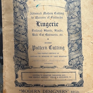May include: A vintage advertisement for a dressmaking course called "Modern Designers" in Brisbane, Australia. The ad features a decorative border with the words "Wisdom and Knowledge" on the left and "Powerful of All Human Things" on the right. The text reads "Advanced Professional Course, Advanced Modern Cutting to Measure of Exclusive Lingerie, Tailored Shorts, Slacks, Bias Cut Garments, etc., Modern Pattern Cutting, The Perfect Method of Cutting to Measure by Tape Measure, Thoroughly Illustrated (Copyright), Cutting to Measure, Designing, etc., "The Perfect Method," which is exclusive to "Modern Designers" Regd., Private Academy of Dressmaking, 2nd Floor, King House, Queen St., Brisbane (Established over 10 years)."