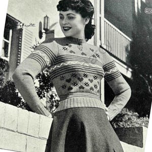 Könnte beinhalten: Ein Schwarzweißfoto einer Frau, die einen gestrickten Pullover mit Herz- und Schneeflockenmuster trägt. Der Pullover hat einen Rundhalsausschnitt und lange Ärmel. Die Frau steht vor einer Backsteinmauer.