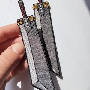 May include: A white ceramic mug with a black handle and the text "But First, Coffee" in a bold, black font. The mug is set against a blurred background. The mug appears to be approximately 10 cm tall.