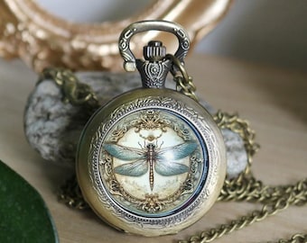 May include: A round, antique-style bronze pocket watch featuring a detailed illustration of a dragonfly with blue-tinted wings centered on the face. The watch is attached to a matching bronze chain and has an ornate, textured metal casing.