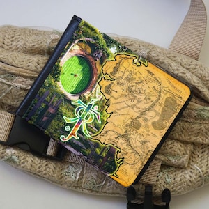 May include: A brown leather wallet with a colorful map of Middle-earth from The Lord of the Rings. The map includes the Shire, Rohan, Gondor, and Mordor. The wallet also features a green door with a round handle, a symbol of the Shire.