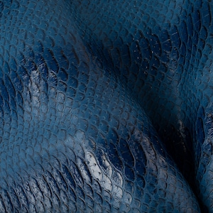May include: Close-up of a textured blue leather material with a scaly pattern.