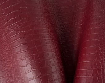 May include: Close-up of a burgundy leather fabric with a crocodile embossed pattern.