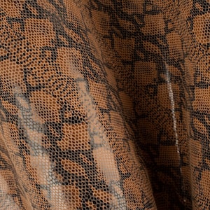 Puede incluir: Primer plano de una tela de piel de serpiente marrón y negra con un patrón texturizado.