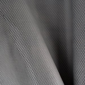 May include: A close-up of a grey, textured fabric with a repeating pattern of small circles. The fabric is folded in a way that creates a wave-like effect.