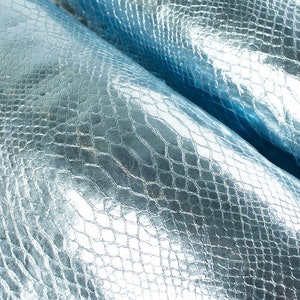 Könnte beinhalten: Nahaufnahme eines hellblauen, strukturierten Kunstleders mit Krokodil-Muster.