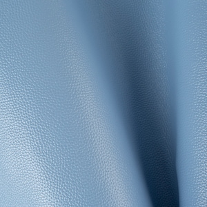 Puede incluir: Primer plano de una tela de cuero texturizada de color azul claro. La tela tiene un brillo sutil y una textura ligeramente granulada.