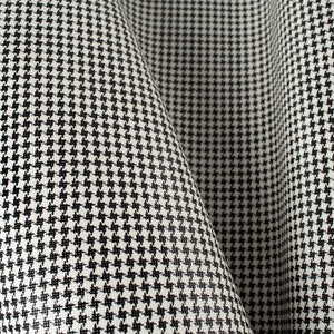 May include: Black and white houndstooth fabric with a textured surface.