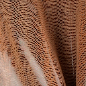 Może przedstawiać: Zbliżenie na brązową skórzaną tkaninę z fakturowanym wzorem w kształcie rombu. Tkanina jest złożona i udrapowana, tworząc miękki, płynny wygląd.