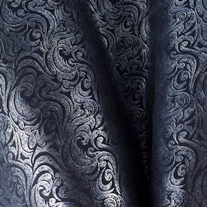 May include: A close-up of a dark blue fabric with a silver embossed pattern of swirling leaves and vines.