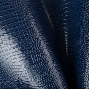 May include: Close-up of a dark blue textured fabric with a crocodile skin pattern.