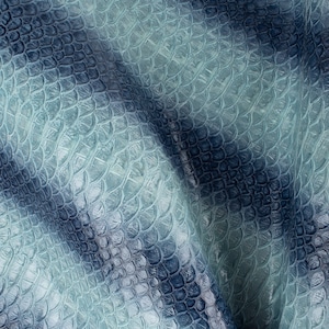 Peut inclure: Gros plan sur un tissu texturé bleu et vert avec un motif peau de crocodile.