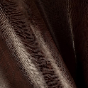 May include: Close-up of a brown faux leather fabric with a textured snake skin pattern.