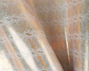 May include: A close-up of iridescent gold fabric with a white lace pattern. The fabric has a shimmery, glittery finish.