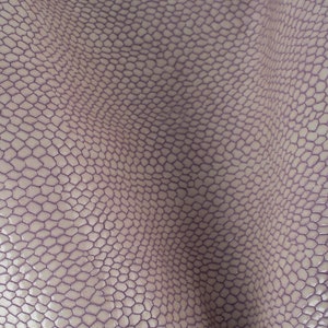 Peut inclure: Gros plan sur un tissu texturé de couleur lilas clair avec un motif de petits hexagones en relief.