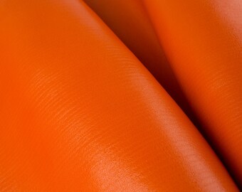 May include: Close-up of vibrant orange leather material, showing the texture and folds of the fabric. The leather has a smooth, glossy finish, and the color is consistent throughout the image.