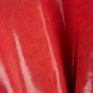 May include: Red textured fabric with a subtle sheen. The fabric has a woven pattern that creates a grid-like appearance.
