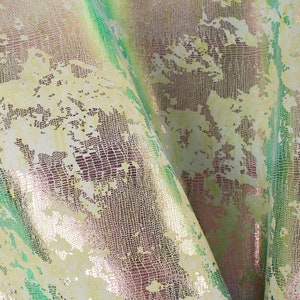 May include: Close-up of a textured fabric with a snakeskin pattern in shades of green, gold, and pink.