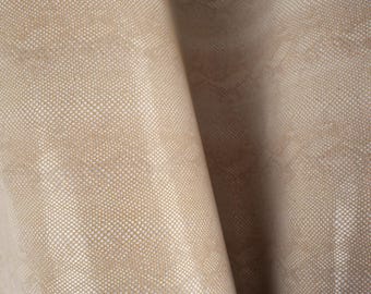 May include: Close-up of a beige fabric with a textured woven pattern. The fabric has a subtle sheen and a slightly rough texture.