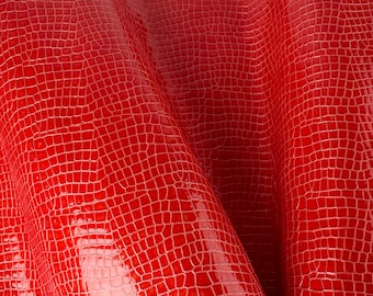 May include: Red textured fabric with a crocodile skin pattern.