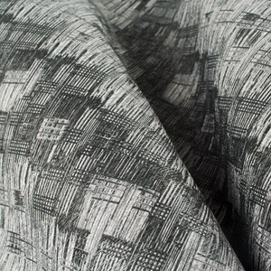 May include: Close-up of a black and white patterned fabric with a textured weave. The fabric has a geometric design with a subtle sheen.