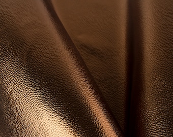 May include: Close-up of a textured, metallic brown leather material. The leather is folded and has a subtle sheen.