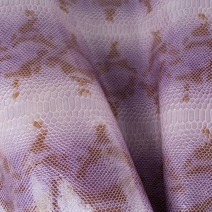 May include: Close-up of a textured fabric with a purple and brown snakeskin pattern.