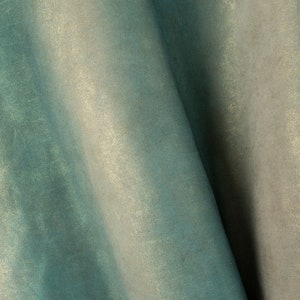 May include: Close-up of a textured fabric with a gradient of teal and off-white hues. The material has a subtle sheen, with folds and shadows adding depth. The overall effect is soft and luxurious.