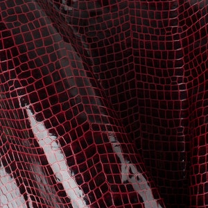 May include: Close-up of a dark red crocodile embossed leather with a glossy finish.