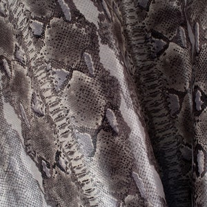 Peut inclure: Gros plan sur un tissu en peau de serpent gris et blanc avec un motif texturé.