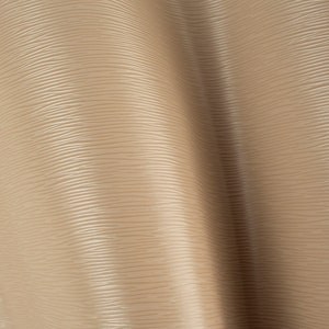 May include: A close-up of a beige textured fabric with a subtle wave pattern. The fabric has a smooth, almost silky feel.