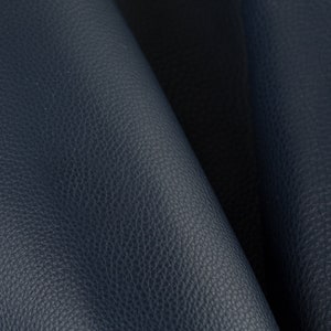 May include: Close-up of a dark blue leather fabric with a textured surface.