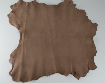 May include: A piece of brown leather, folded and laid flat on a white surface.