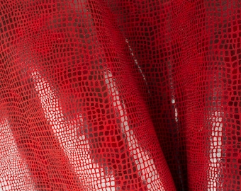 May include: Red faux leather fabric with a snakeskin pattern. The fabric has a subtle shimmer.
