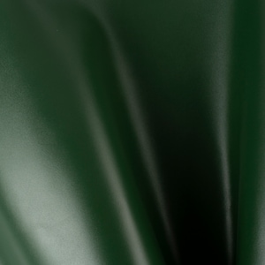 Puede incluir: Primer plano de una tela verde oscuro con una textura suave y sedosa. La tela está doblada en el centro, creando una forma de V.