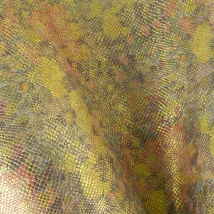 Può includere: Un tessuto strutturato con un motivo a pelle di serpente in tonalità oro, verde e rosso.