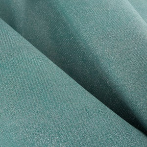 May include: Close-up of a teal fabric with a subtle shimmer. The fabric has a textured, woven appearance.