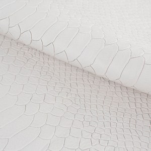 Puede incluir: Tela de piel sintética blanca con un patrón texturizado y estampado que se asemeja a la piel de cocodrilo.