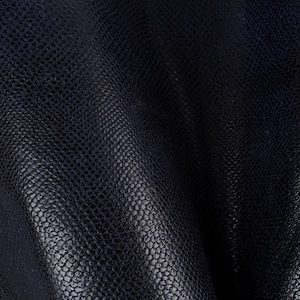 Peut inclure: Gros plan sur un tissu texturé bleu foncé avec un léger brillant. Le tissu a un motif caillouteux ou gaufré, ressemblant aux écailles d'un reptile.