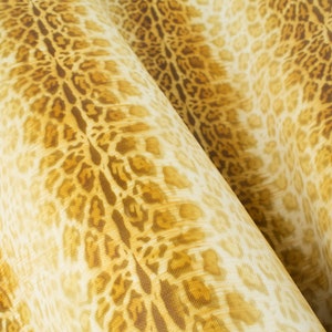 May include: Close-up of a fabric with a brown and yellow leopard print pattern. The fabric is folded in half, creating a textured look.