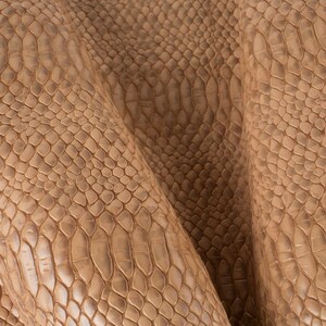 Puede incluir: Primer plano de una tela texturizada con un patrón de piel de serpiente en color marrón claro.