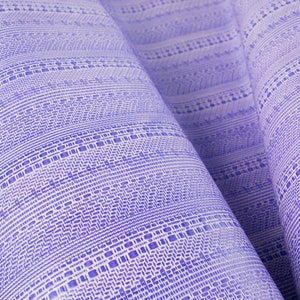 May include: Close-up of a purple and white woven fabric with a repeating geometric pattern.