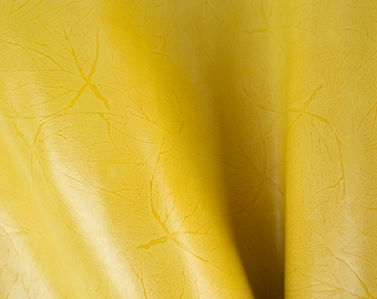 Peut inclure: Un tissu jaune avec un motif de feuilles en relief sur la surface. Le tissu est plié et a un aspect doux et texturé.