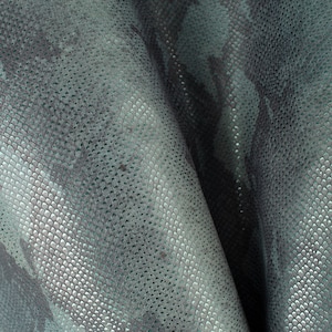 May include: Close-up of a teal-coloured fabric with a textured, snake-skin pattern.