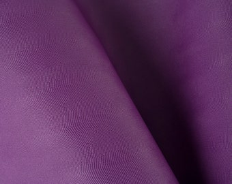 Pode incluir: Close-up de um tecido roxo com uma superfície texturizada. O tecido está dobrado ao meio, criando um drapeado suave e fluido.