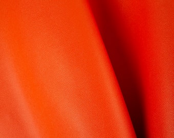 May include: Close-up of a bright orange leather fabric with a textured surface.